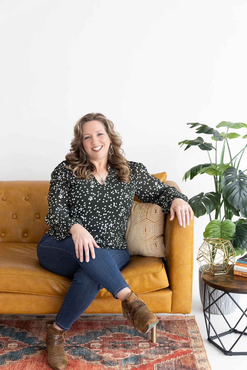 A family therapist in Plano sits on a couch while having a conversation with a client.