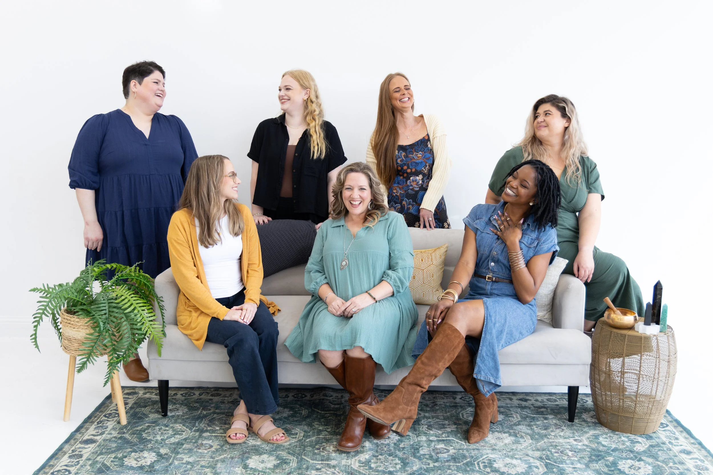 Trauma-informed group therapists in Plano sit together on a couch and laugh.