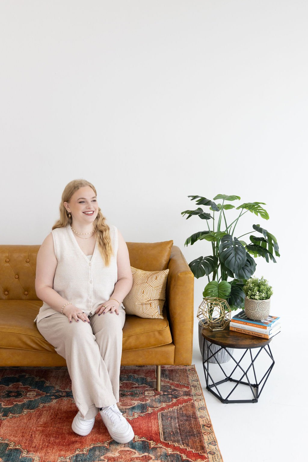 A counselor who provides relationship therapy in Dallas sits on a couch gazing out the window.