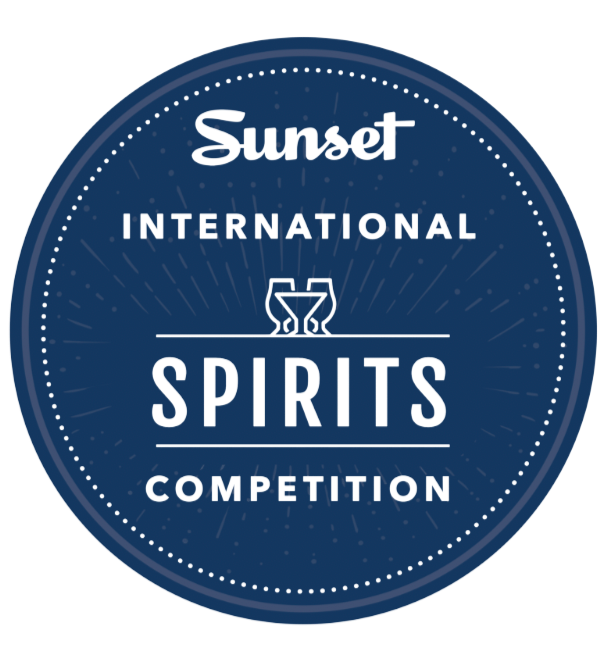Blue circular logo for Sunset International Spirits Competition with text and a stylized glass icon in the center.