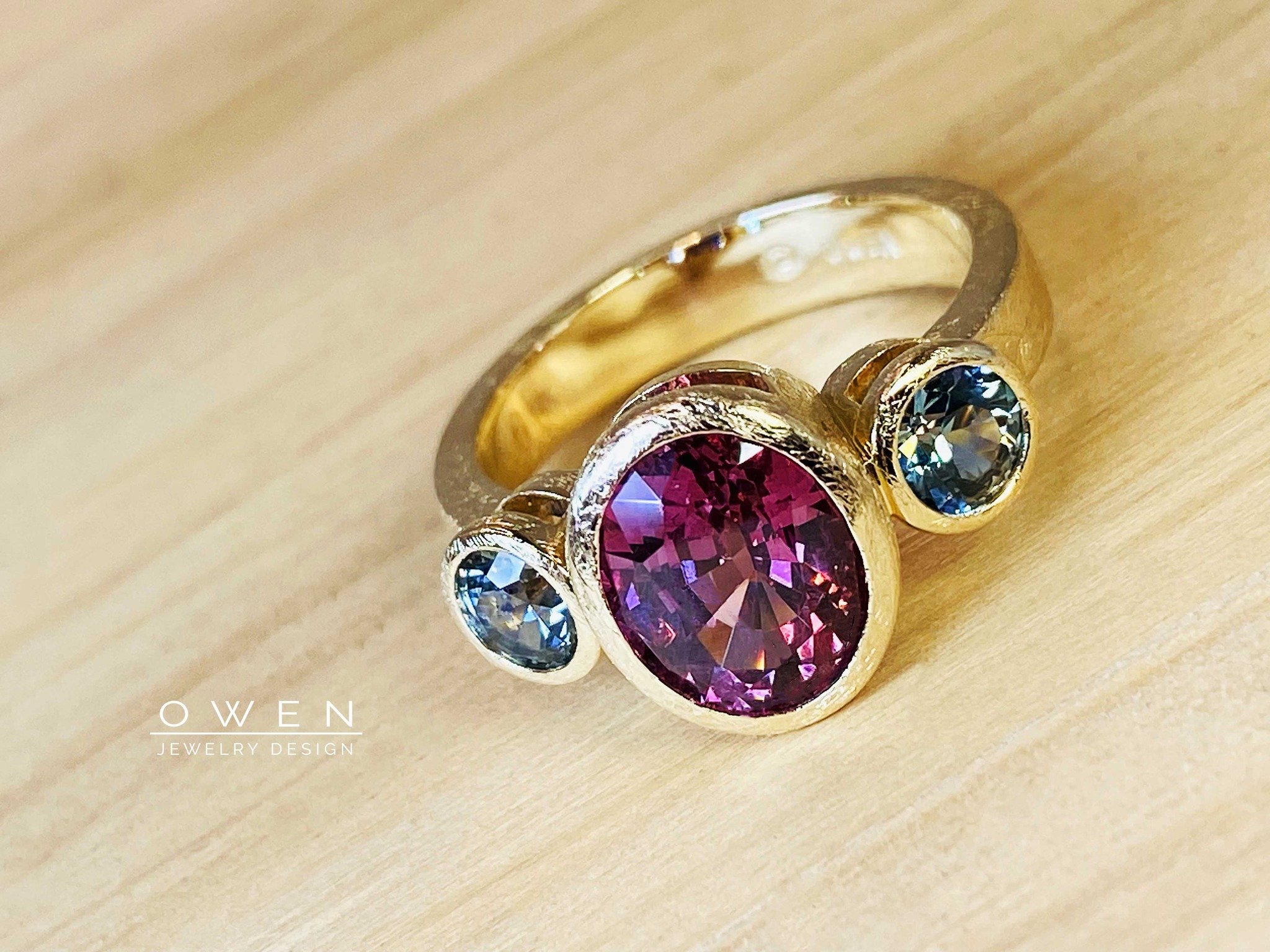 CUSTOM YELLOW GOLD RING WITH AN OVAL GARNET AND MONTANA SAPPHIRES.jpg