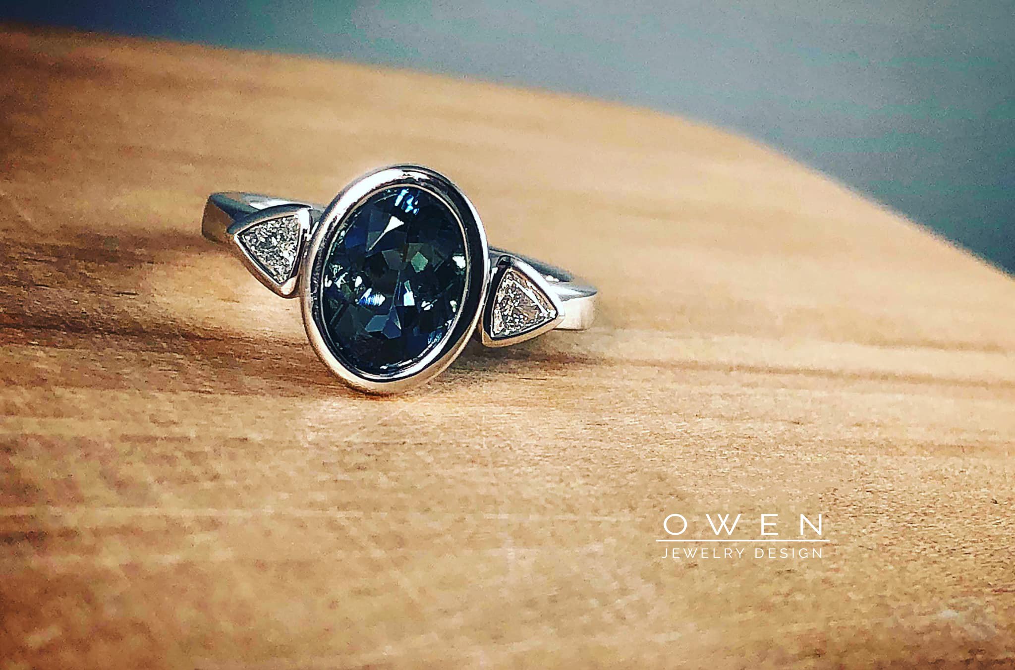 CUSTOM WHITE GOLD RING WITH A BRAZILIAN AQUAMARINE AND TWO TRILLIAN ACCENT DIAMONDS.jpg