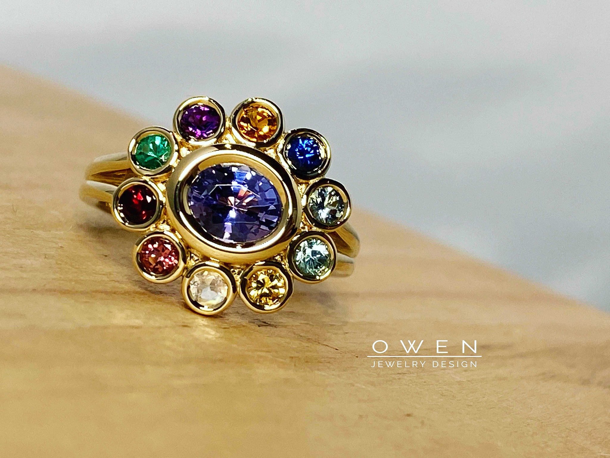 CUSTOM YELLOW GOLD RING WITH TANZANITE AND A HALO OF GENUINE GEM STONES.jpg