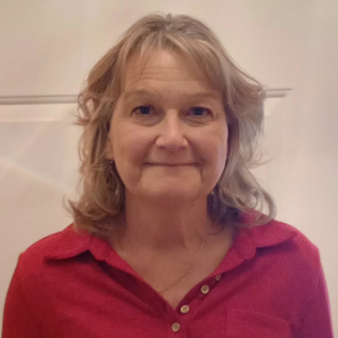 Woman with shoulder length blonde hair wearing a red collared shirt