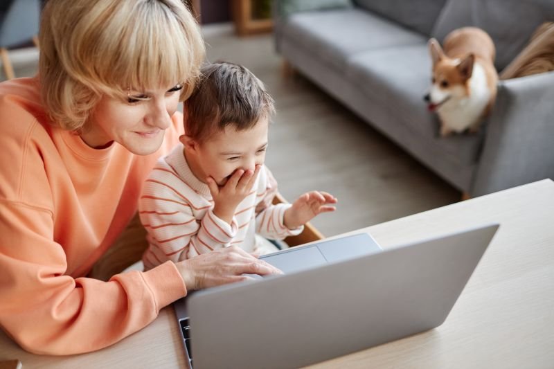 Top view portrait of Little boy with down syndrome using computer with mom