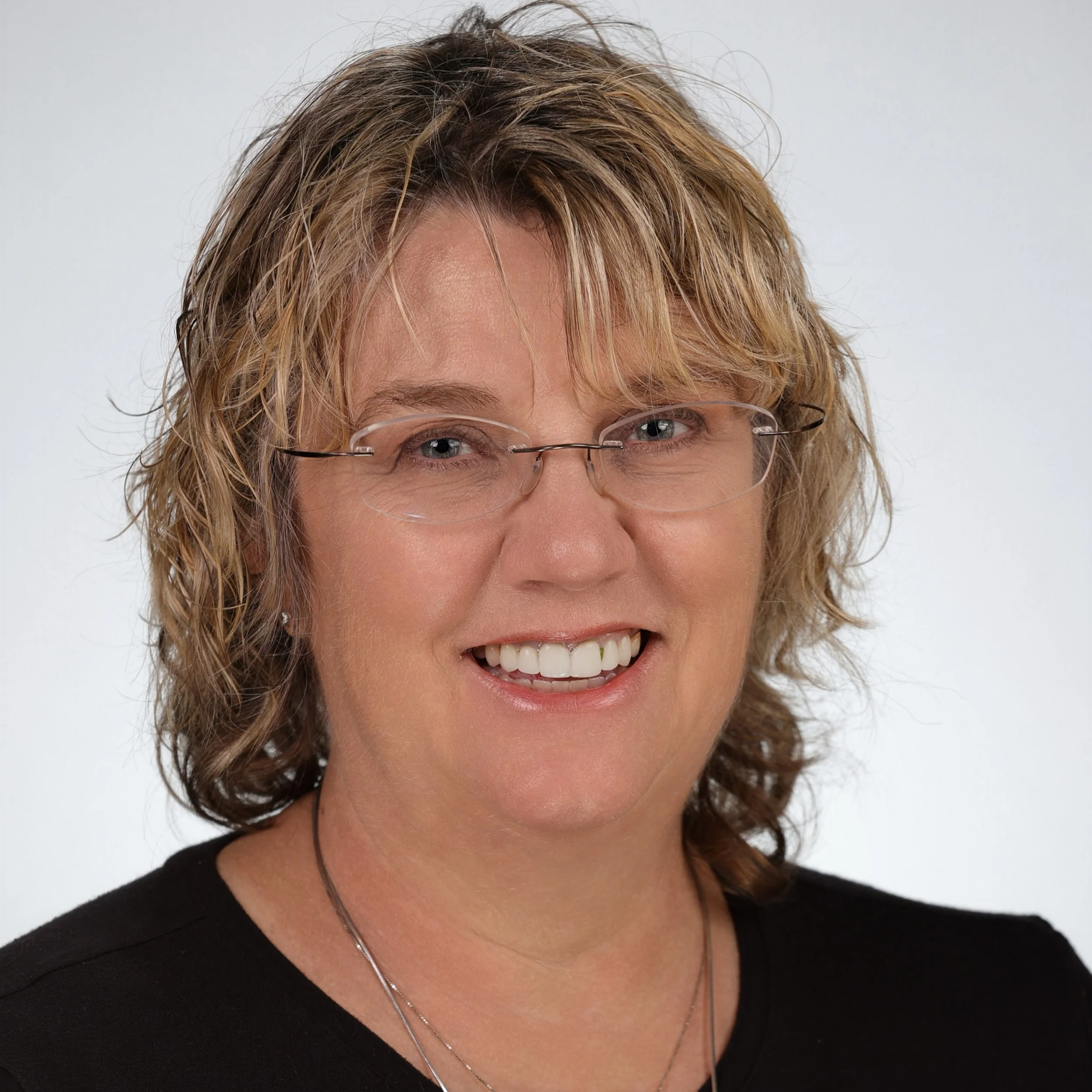 White woman with short curly blonde hair and glasses