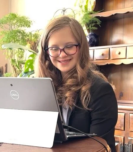 Woman with blonde hair and glasses sitting at a computer