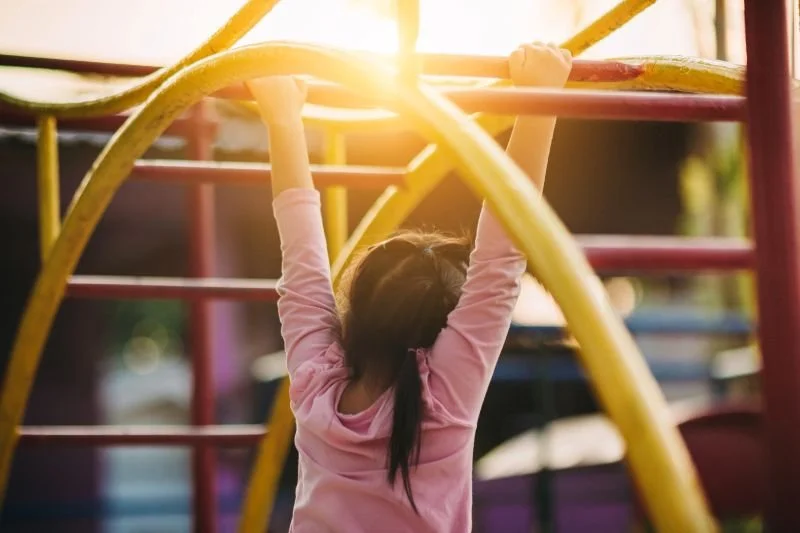 young girl swinging from a jungle gym