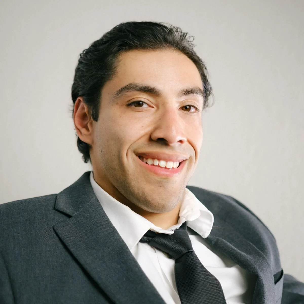 Man  with dark hair wearing a gray suit and tie