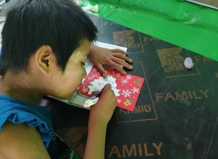 Child writing a Christmas wish card at a CNMN party