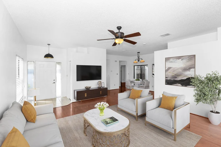 Modern living room with white walls, white sofa with yellow pillows, two white armchairs with yellow pillows, wooden cof
