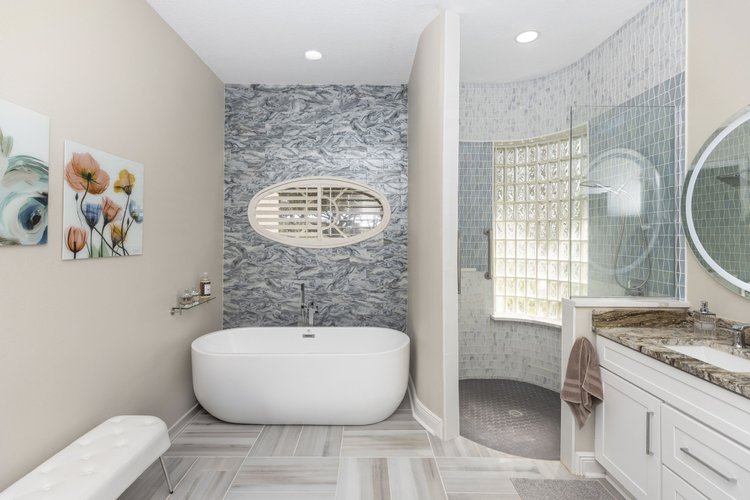 Modern bathroom with a freestanding bathtub, a corner shower with glass blocks, and a vanity with a marble countertop.
