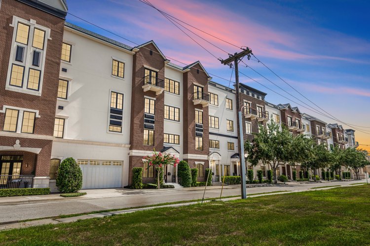 Residential apartment complex with multiple stories, brick and white exterior, small balconies, and front door entrances