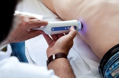 A medical professional uses a handheld device to perform an ultrasound on a person's abdomen.