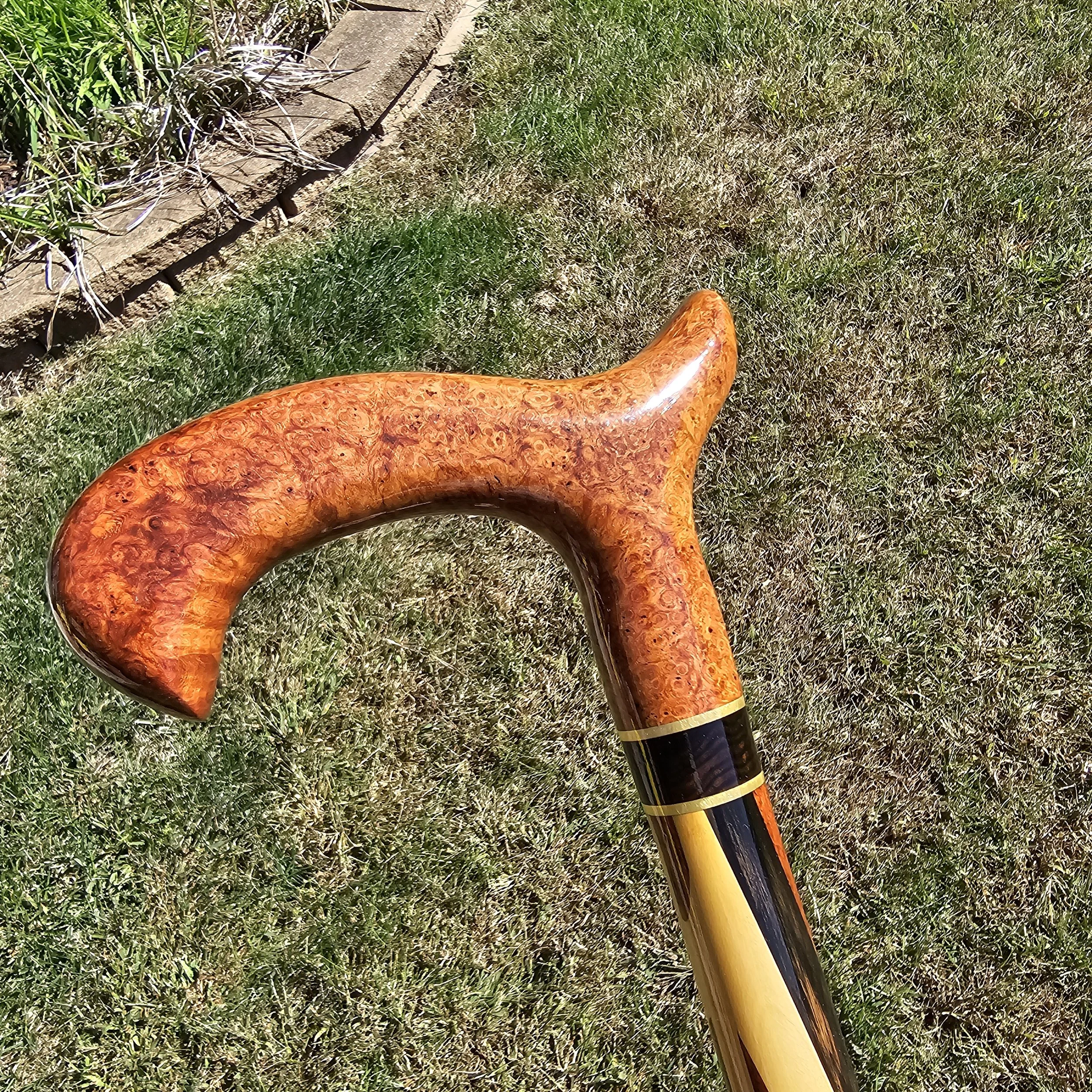Walking cane with a glowing orange Amboyna Burl handle and a body striped in orange Narra, yellow yellowheart and black ebony.