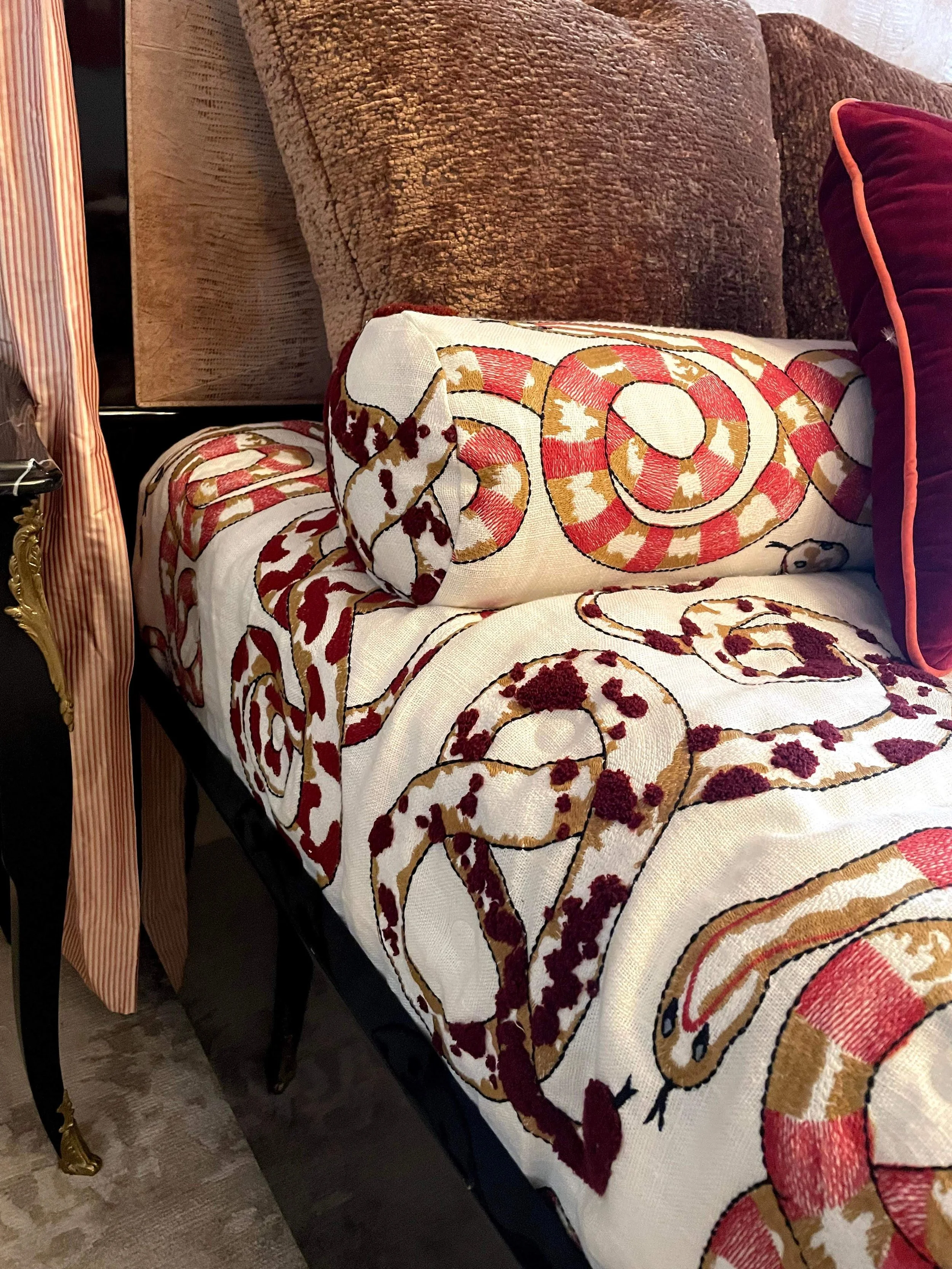 Embroidered snake print bedding and matching round lumbar pillow.  Other bed pillows are pink with contrast welt detail.