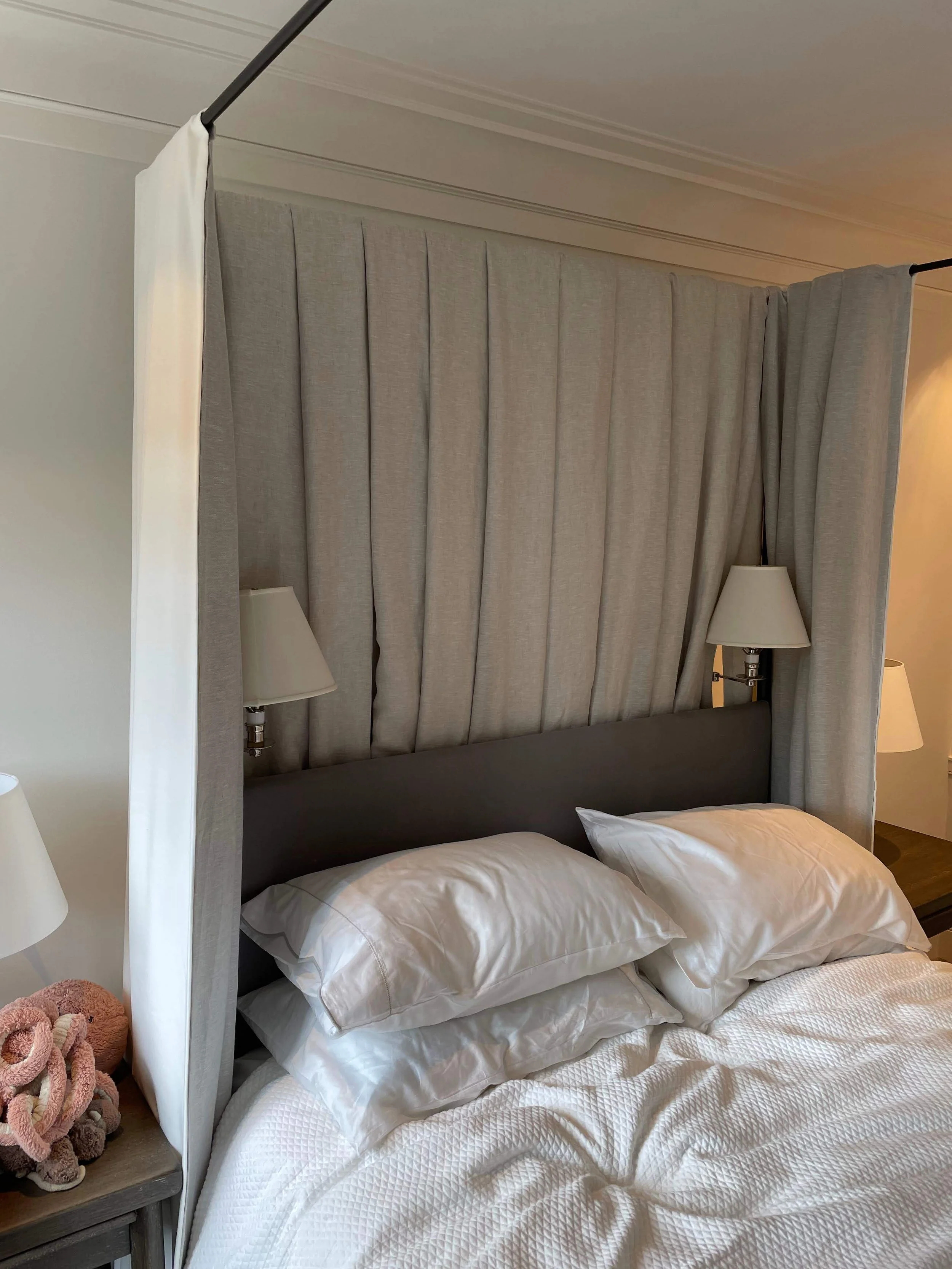 Four post bed with custom drapery panel at the head of the bed and built-in reading sconces