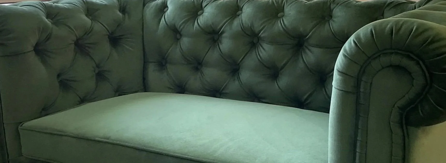 A green button-tufted velvet sofa with rolled arms. Created by LP Studio in Woodinville, WA.