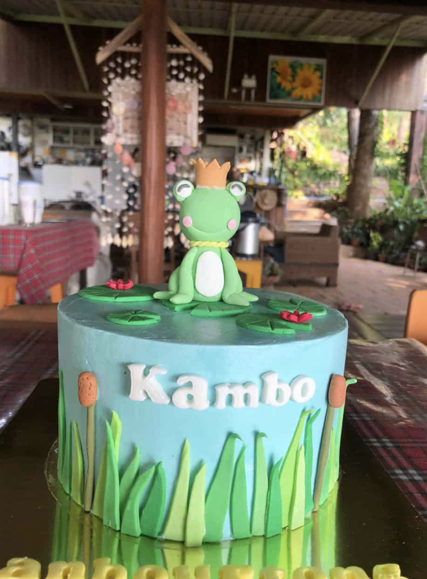 Cake decorated with a frog wearing a crown, sitting on lily pads, with the name "Kambo" on the side.