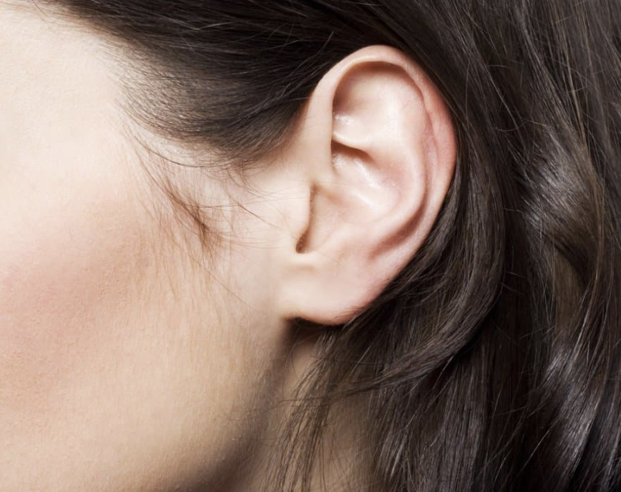 Close-up of a human ear with dark hair