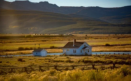 A rural property with houses, a pond, fencing, and open countryside.