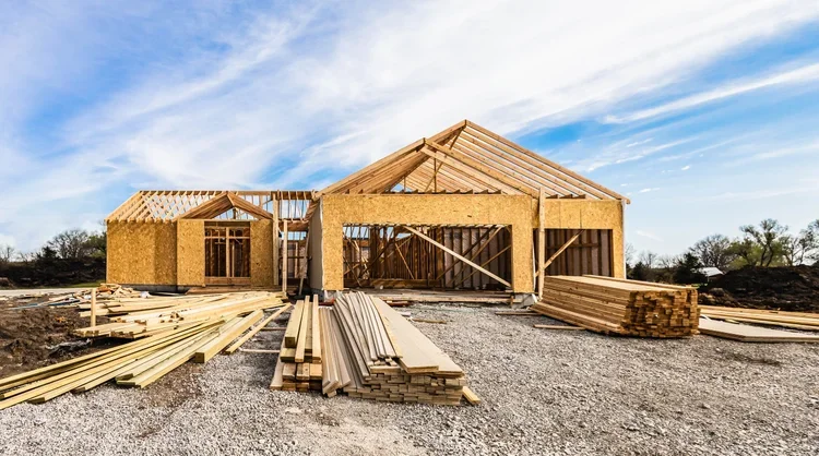 A house under construction with exposed framing and building materials.
