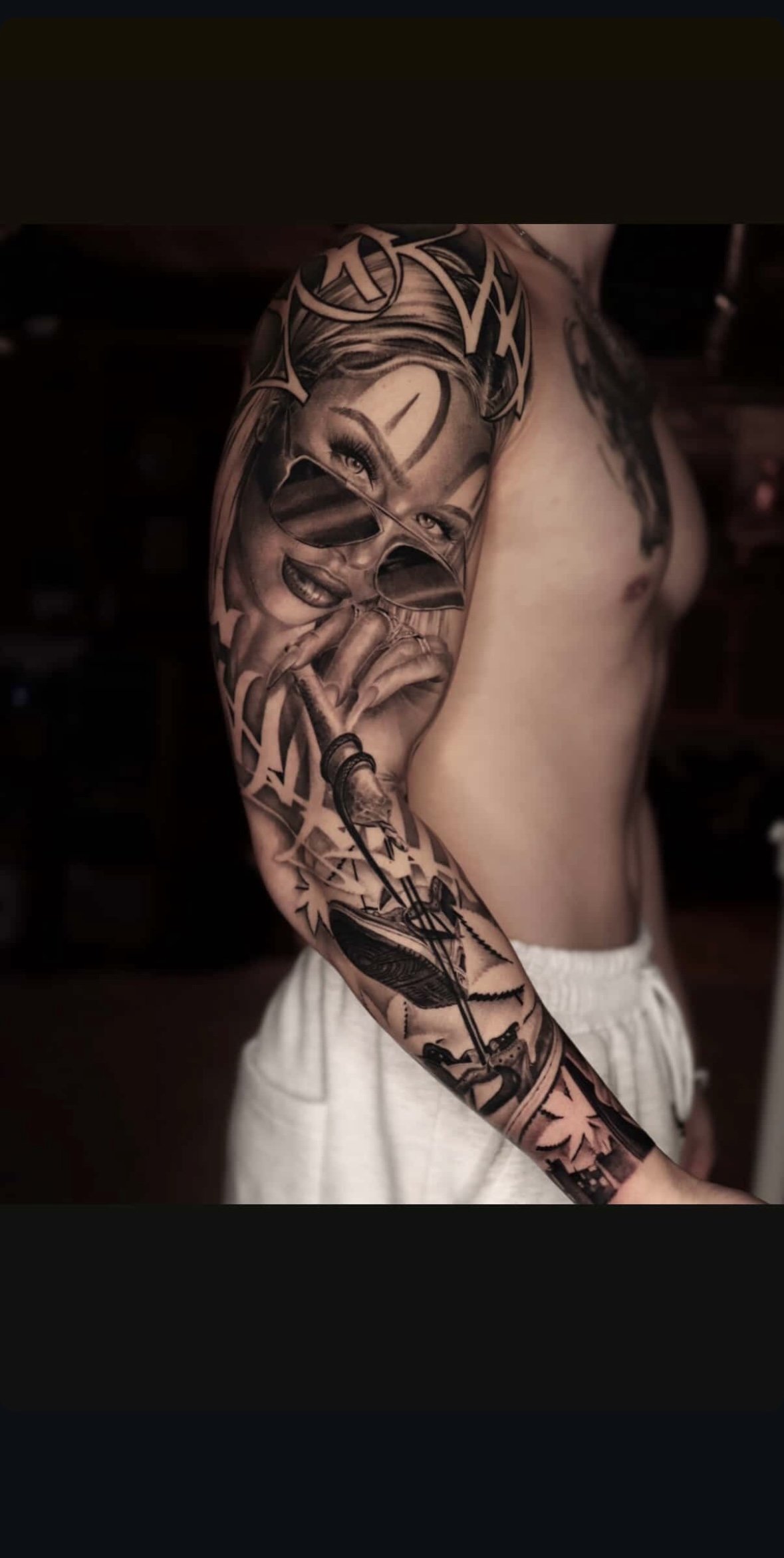 Black and gray detailed sleeve tattoo featuring a woman with sunglasses, holding a finger to her lips, with various design elements including geometric shapes and a cityscape.