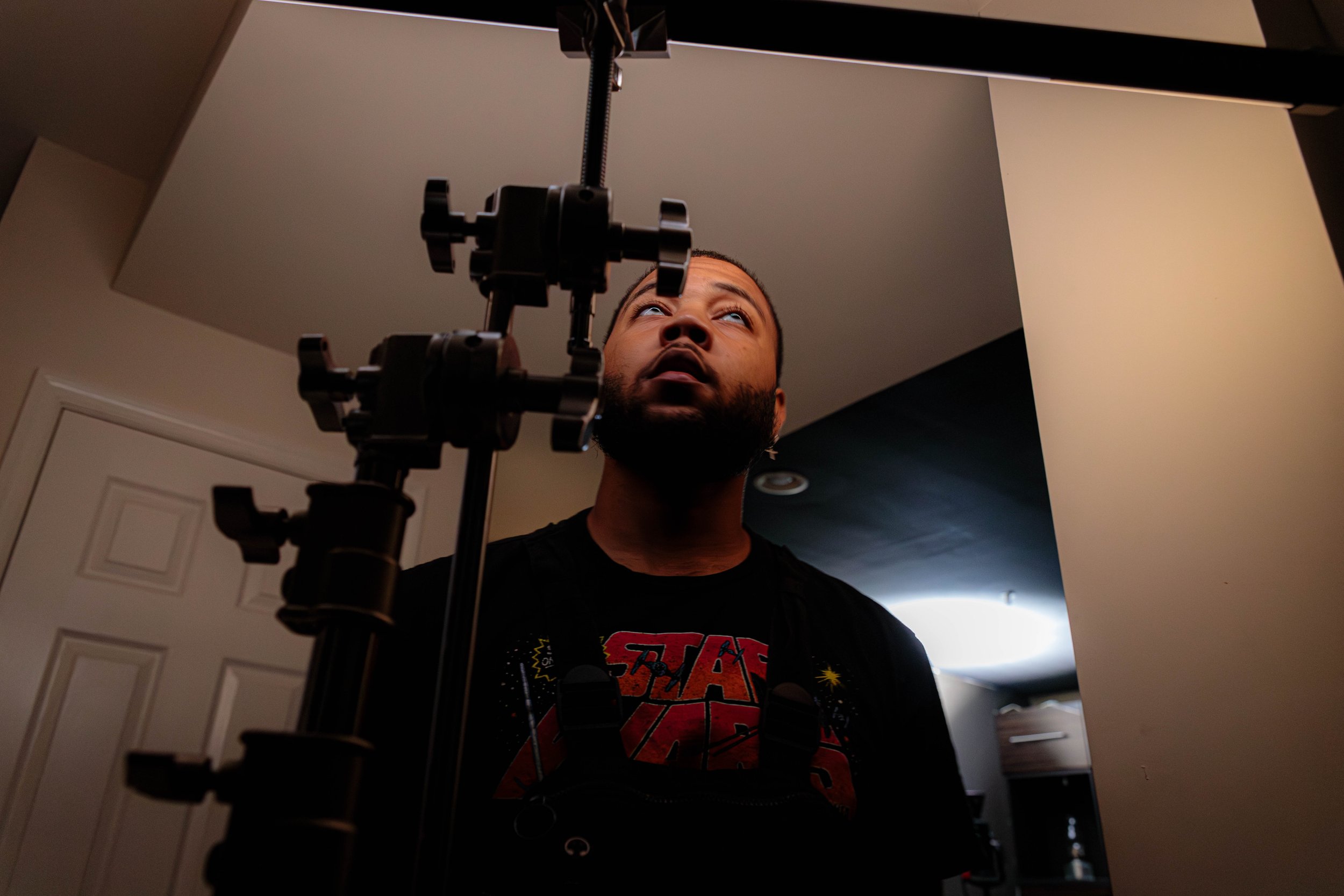Gaffer looking upward at tube light, mounted on C-stand