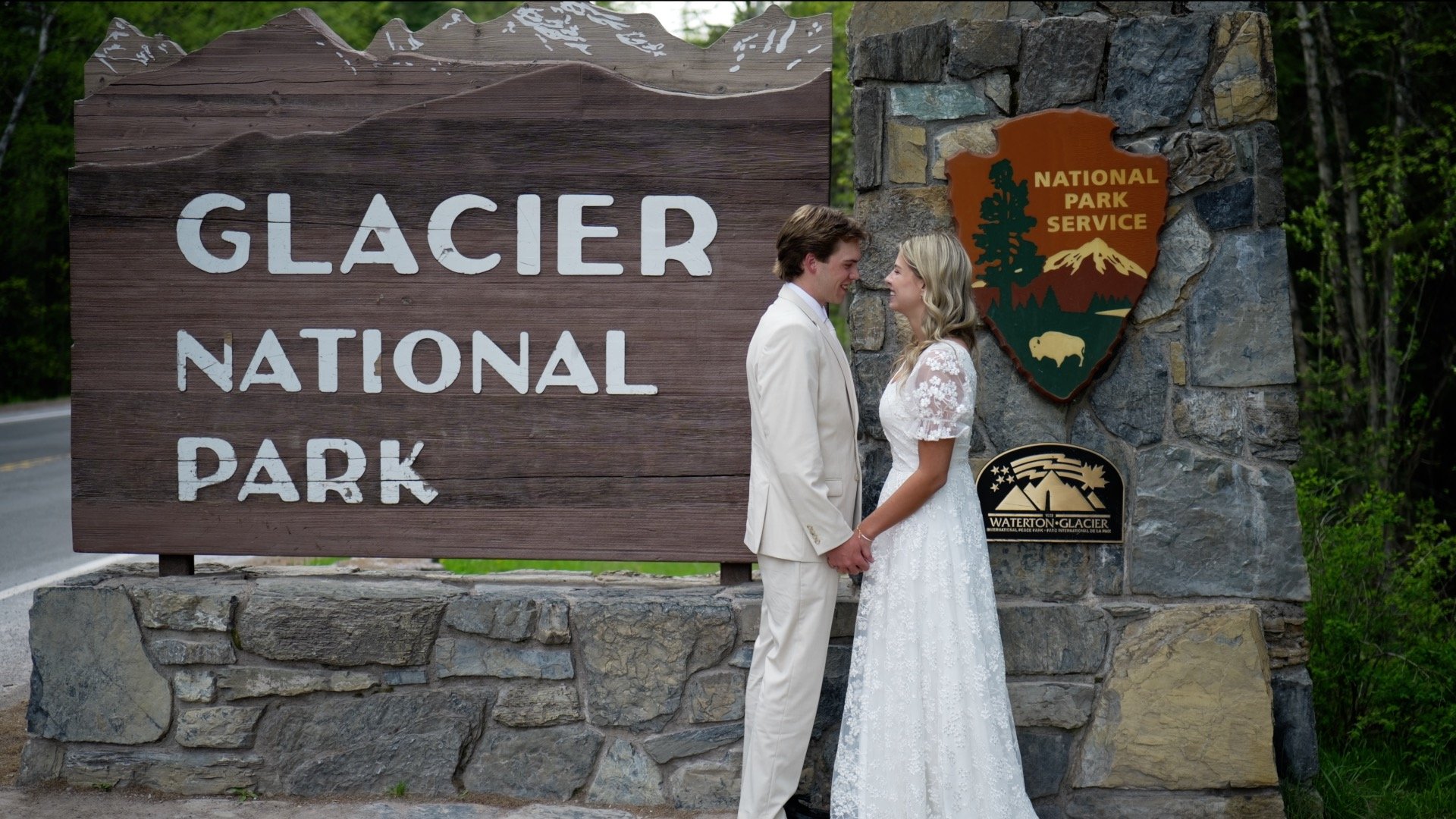 bride and groom standing in front of the glacier national park sign after they got married | Glacier National Park Erickson Media Videographer