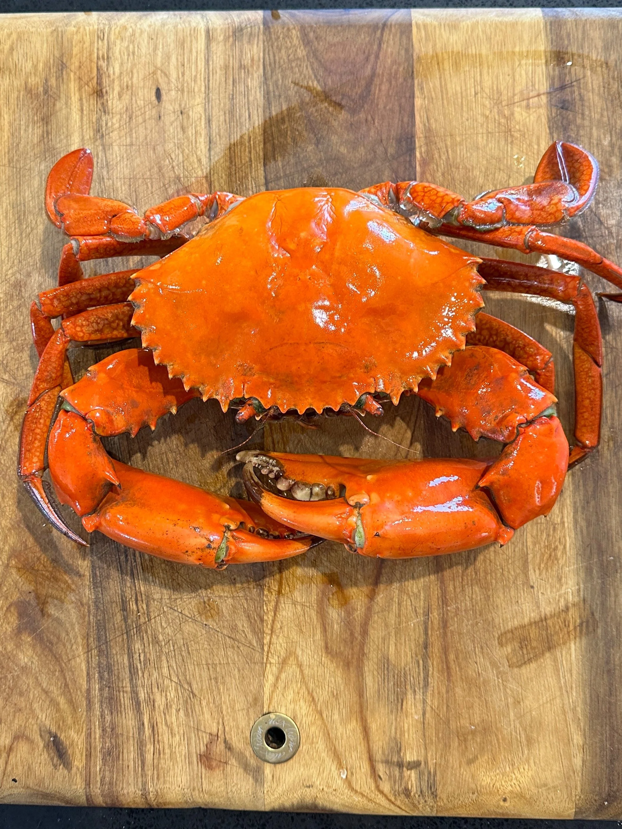 Cooked orange crab on a wooden cutting board.