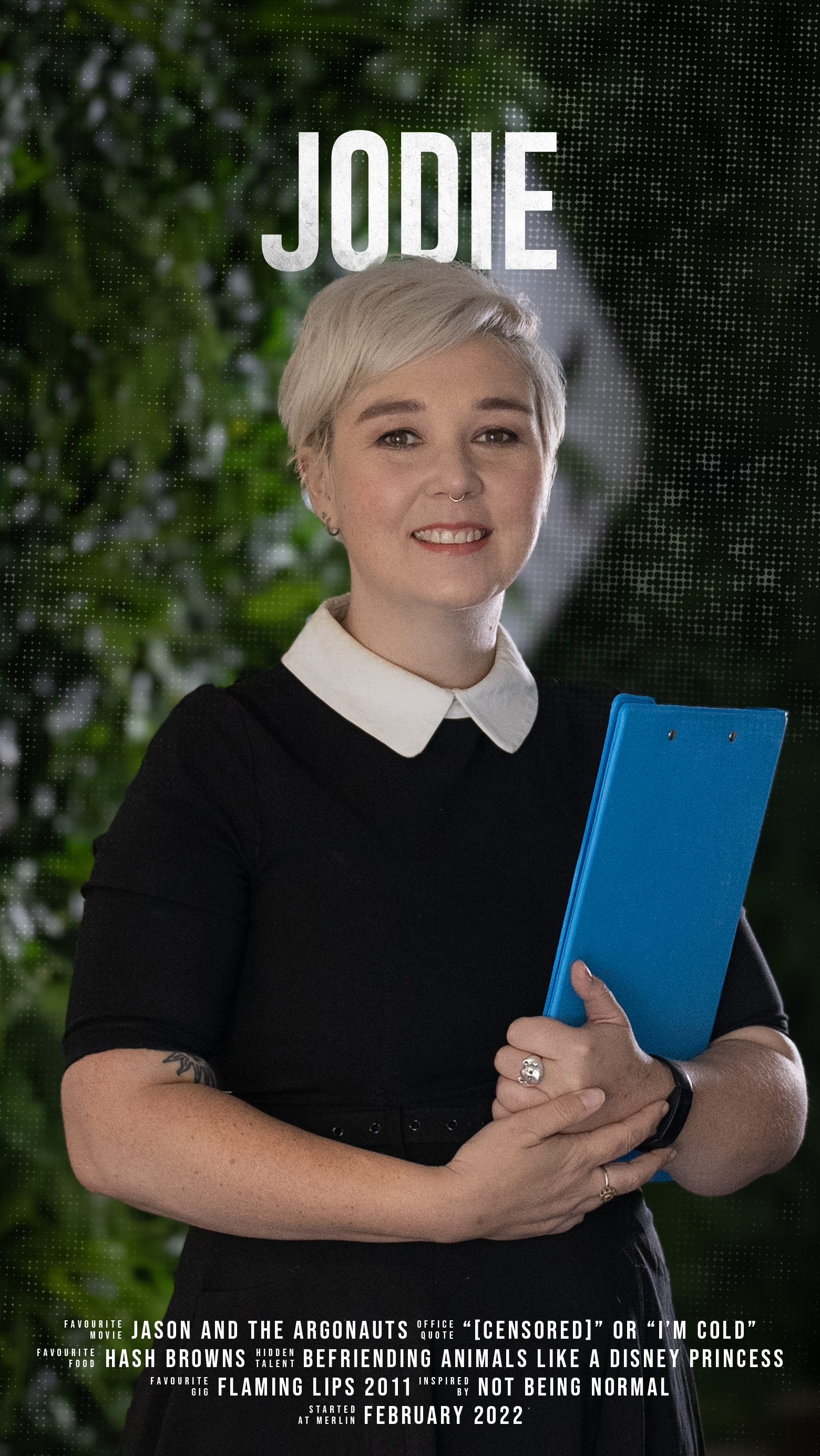 A woman with short blonde hair, wearing a black dress with a white collar, holding a blue clipboard, standing in front of a leafy green background with the name 'Jodie' displayed above her head.