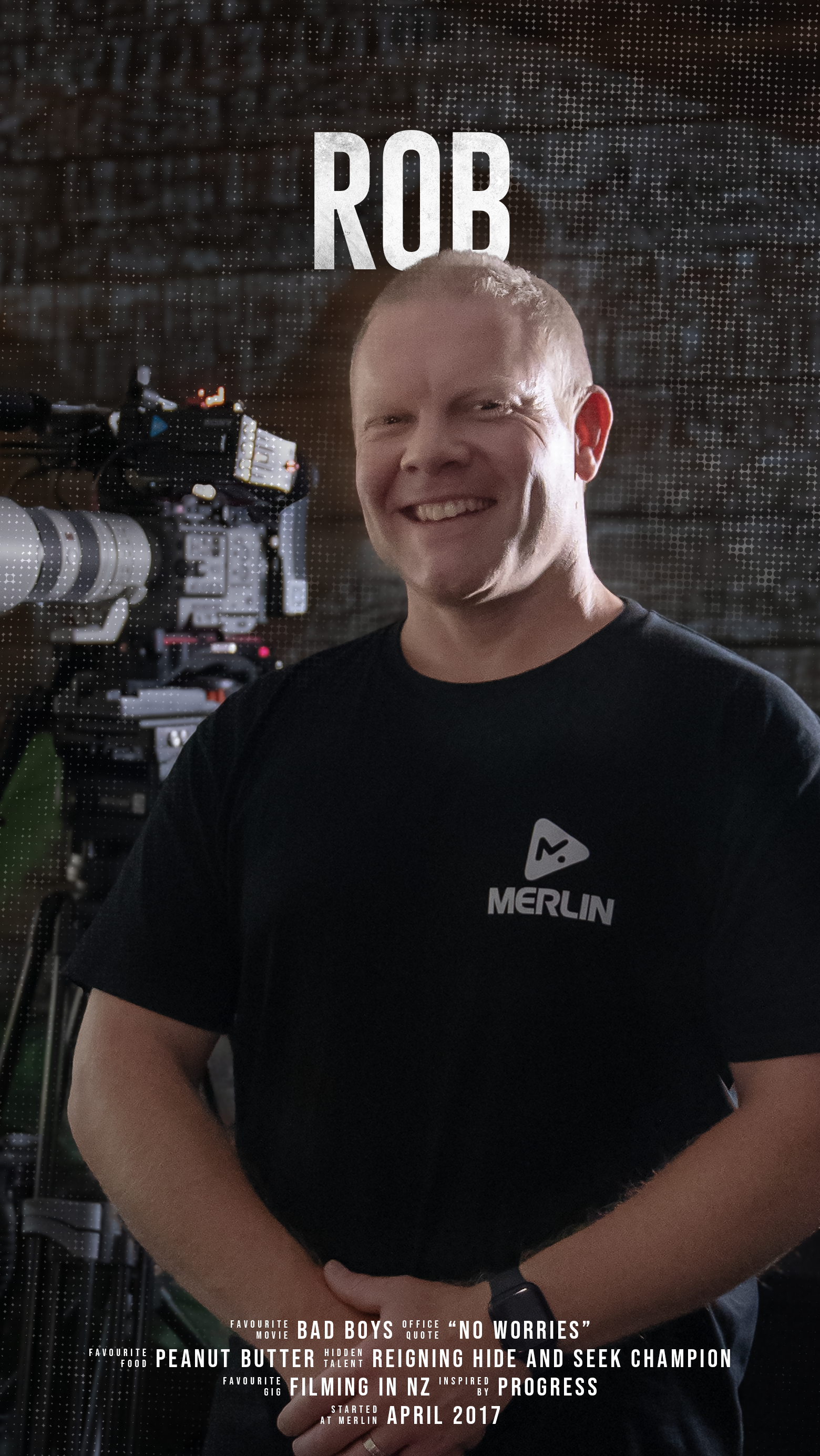 A man smiling and standing in front of a camera and a brick wall, wearing a black T-shirt with the Merlin logo, with the name Rob and text about a film project.