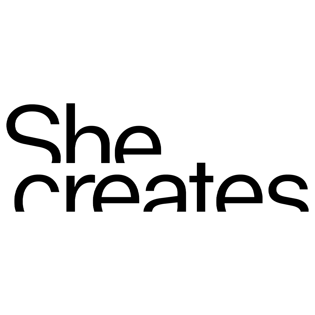 Black text on a transparent background reads: "she creates."