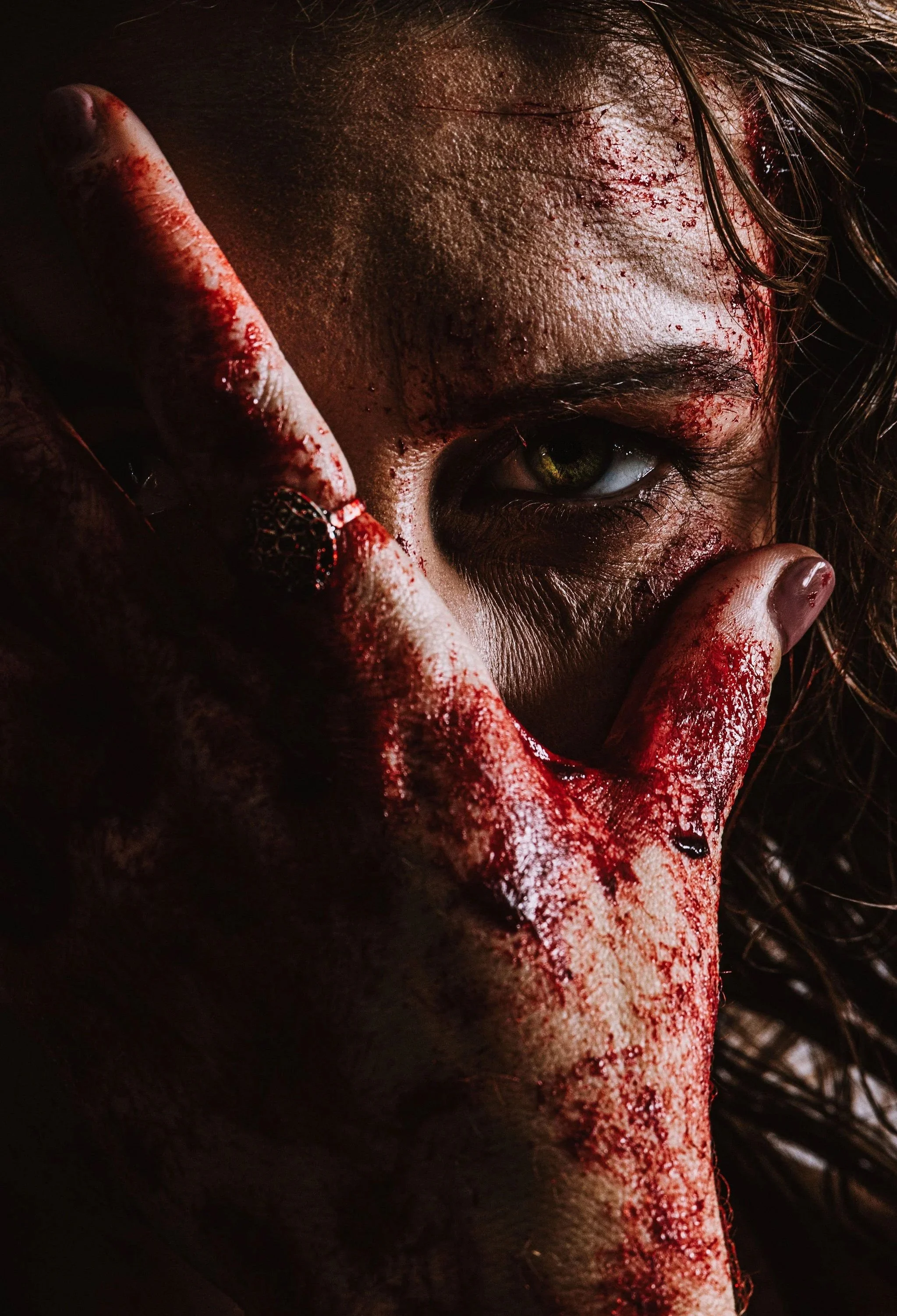 Unit still of actor Jemma Evans as Noah in the film Incorrigible, with a blood-covered hand obscuring her face in a dark horror scene. Key art photo by Ray Kuglar.