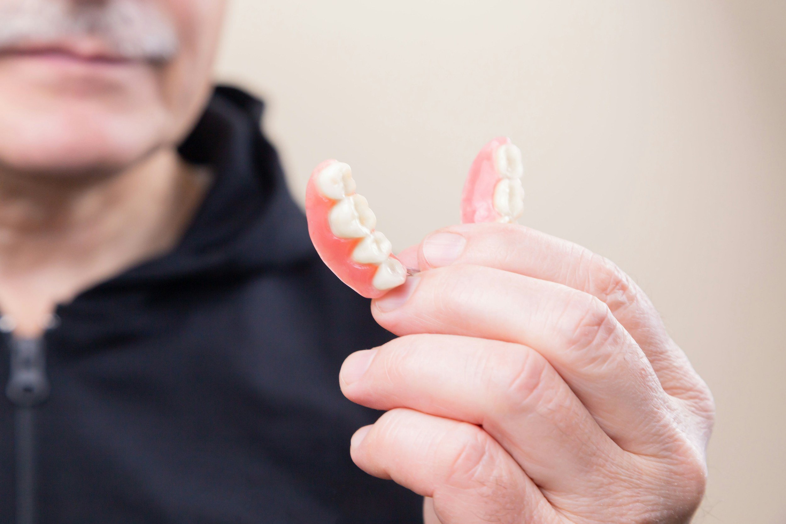 Close-up of an elderly person holding dentures