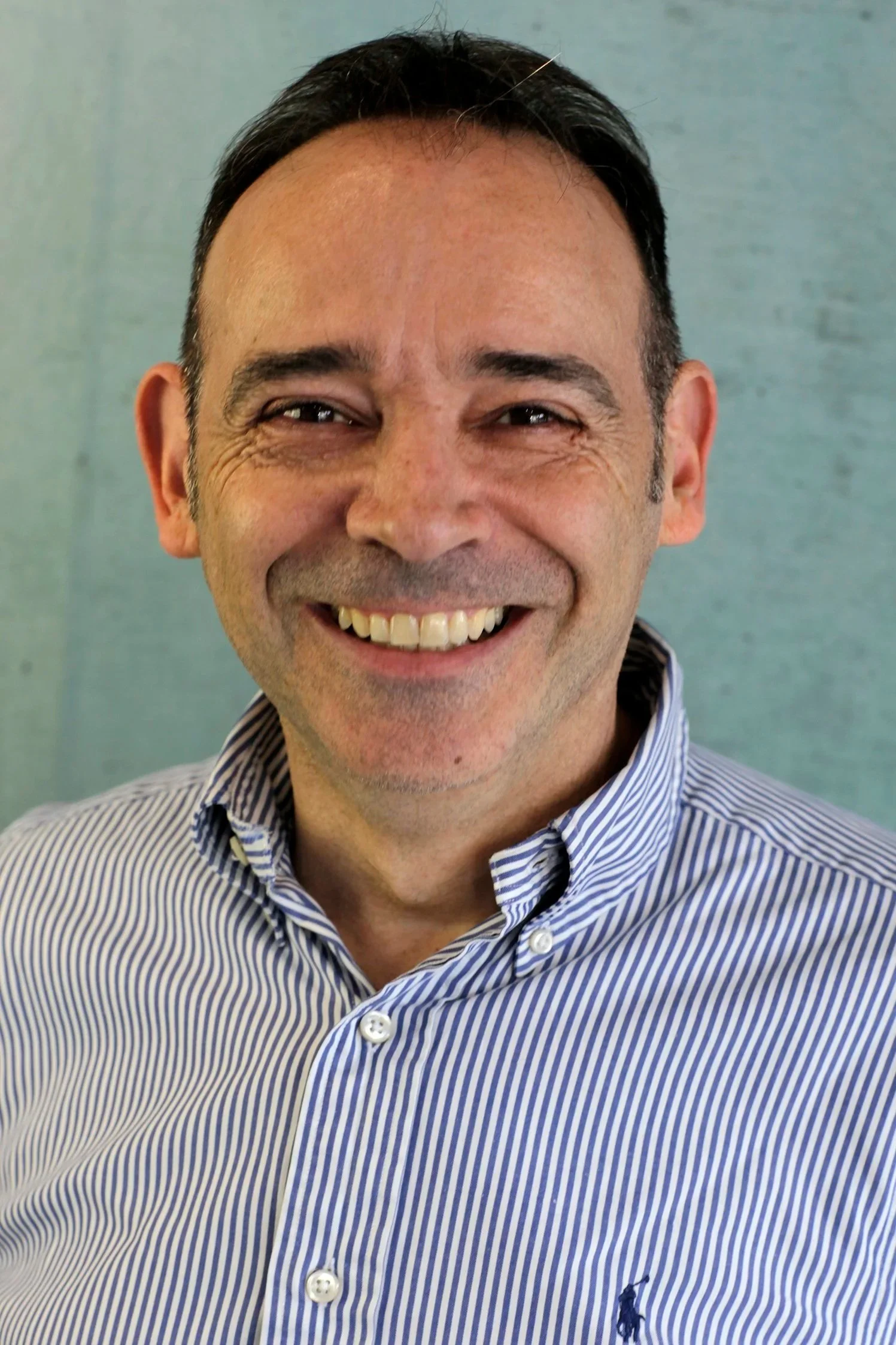 Smiling man in striped shirt against gray background