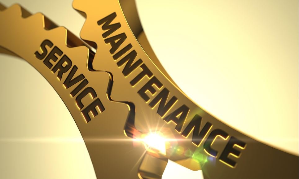 Close-up of gold gear with engraved text 'Maintenance Service' and sunlight reflecting off it.