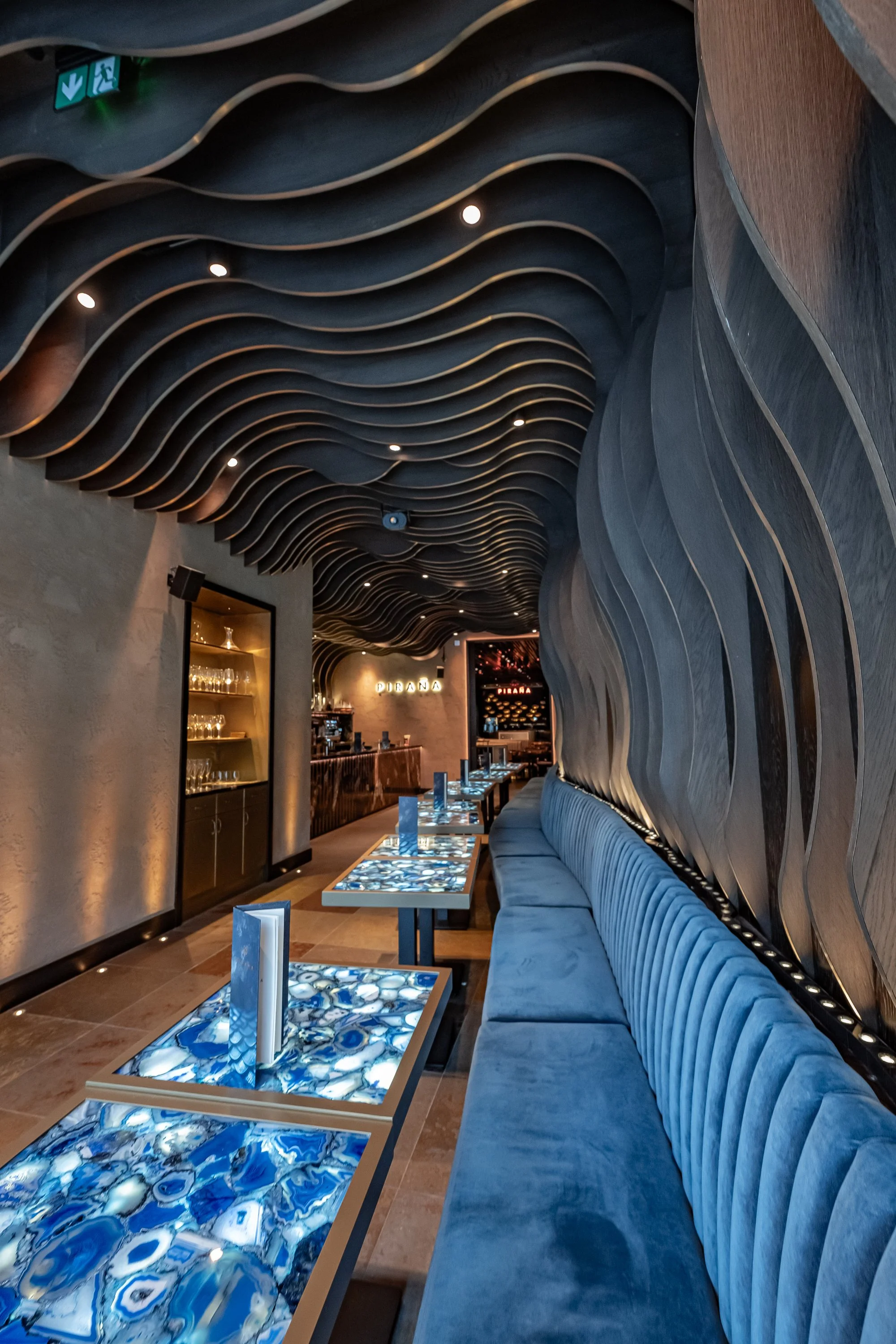 Piraña interior with long blue banquette and curved ceiling and wall features.