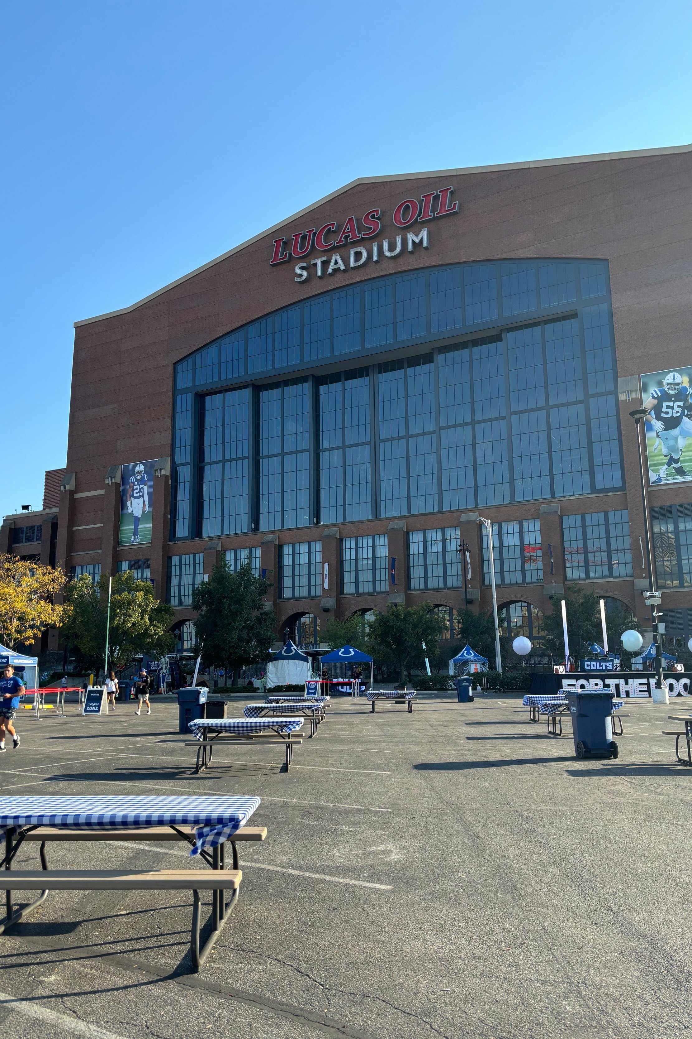 Lucas Oil Stadium with picnic tables and tents in the foreground on a sunny day. Bringing the excitement to events with our professional airbrush tattoo services—book today!