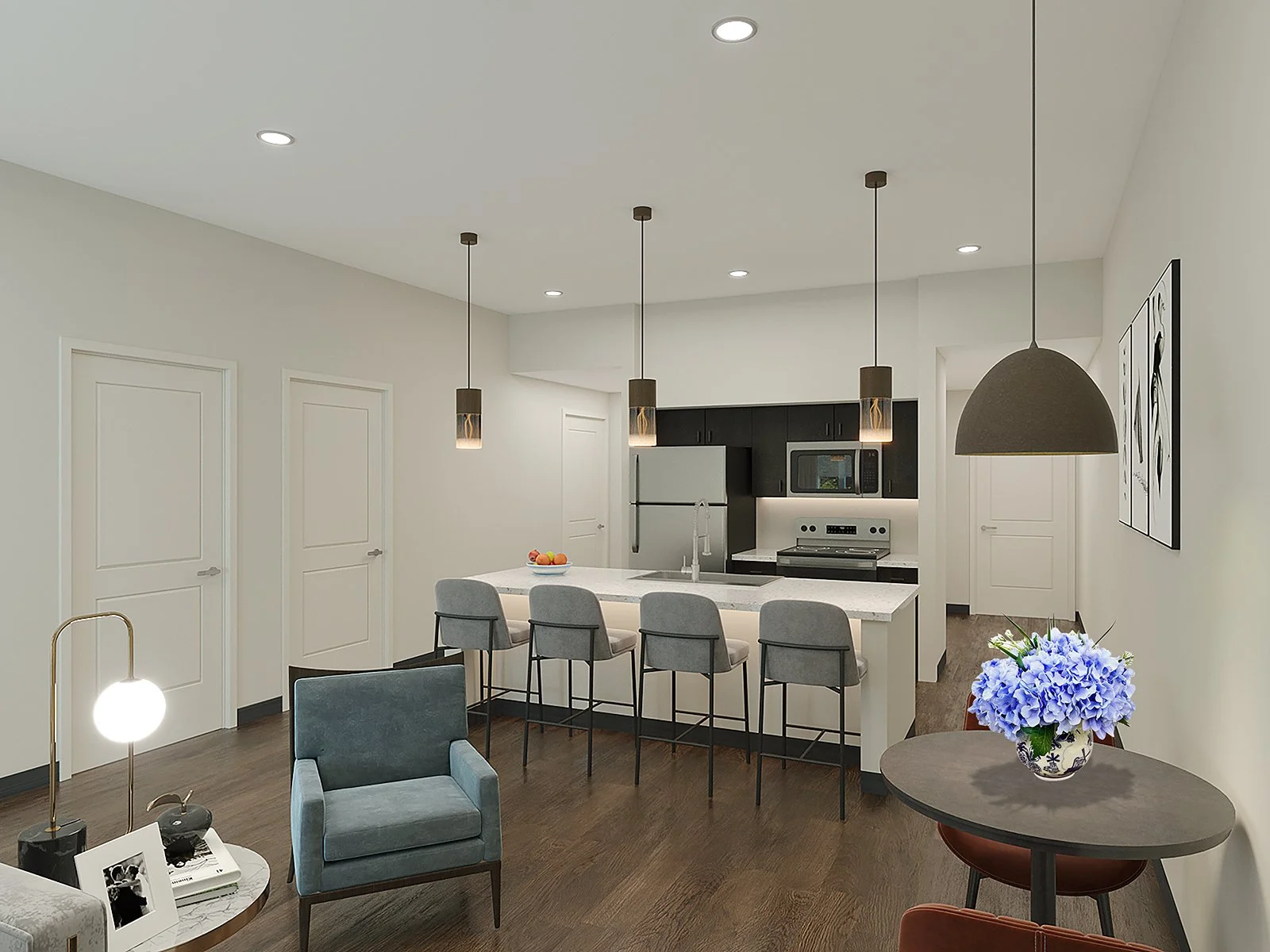 Modern kitchen with black cabinets, stainless steel appliances, and an island with four chairs. There are three pendant lights above the island and a large black dome pendant light over a small round table with a blue hydrangea flower arrangement. The room has white walls and dark wood flooring.