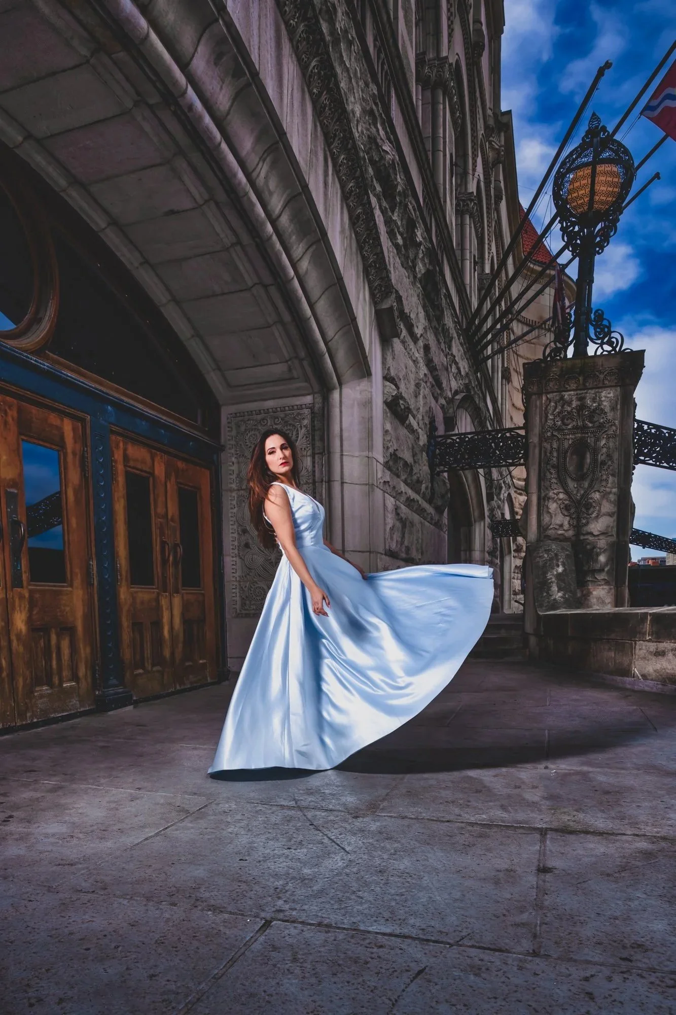 High school senior in a flowing white dress posing outside Union Station at dusk.