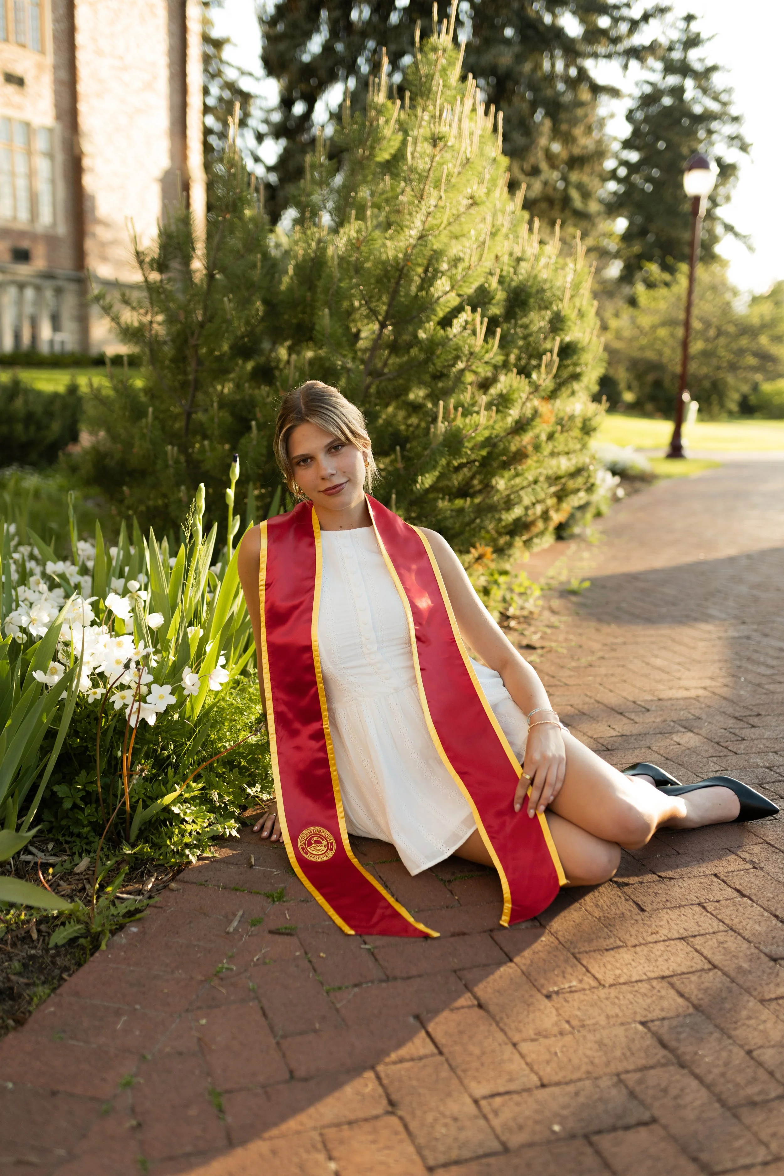 University of Denver graduate sitting in greenery during a graduation photo session with a timeless, vibrant aesthetic. Editorial graduation portrait of a University of Denver senior sitting in greenery with a timeless and clean composition