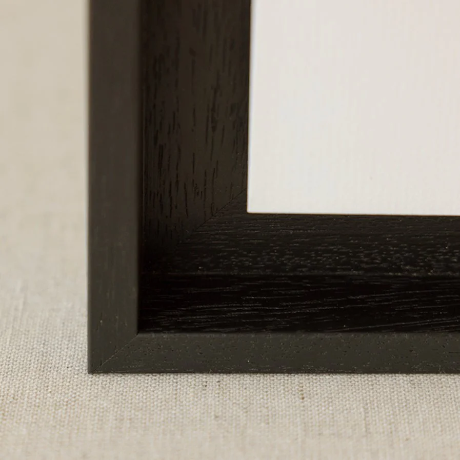 Close-up photo of a black picture frame corner on a light-colored fabric surface.