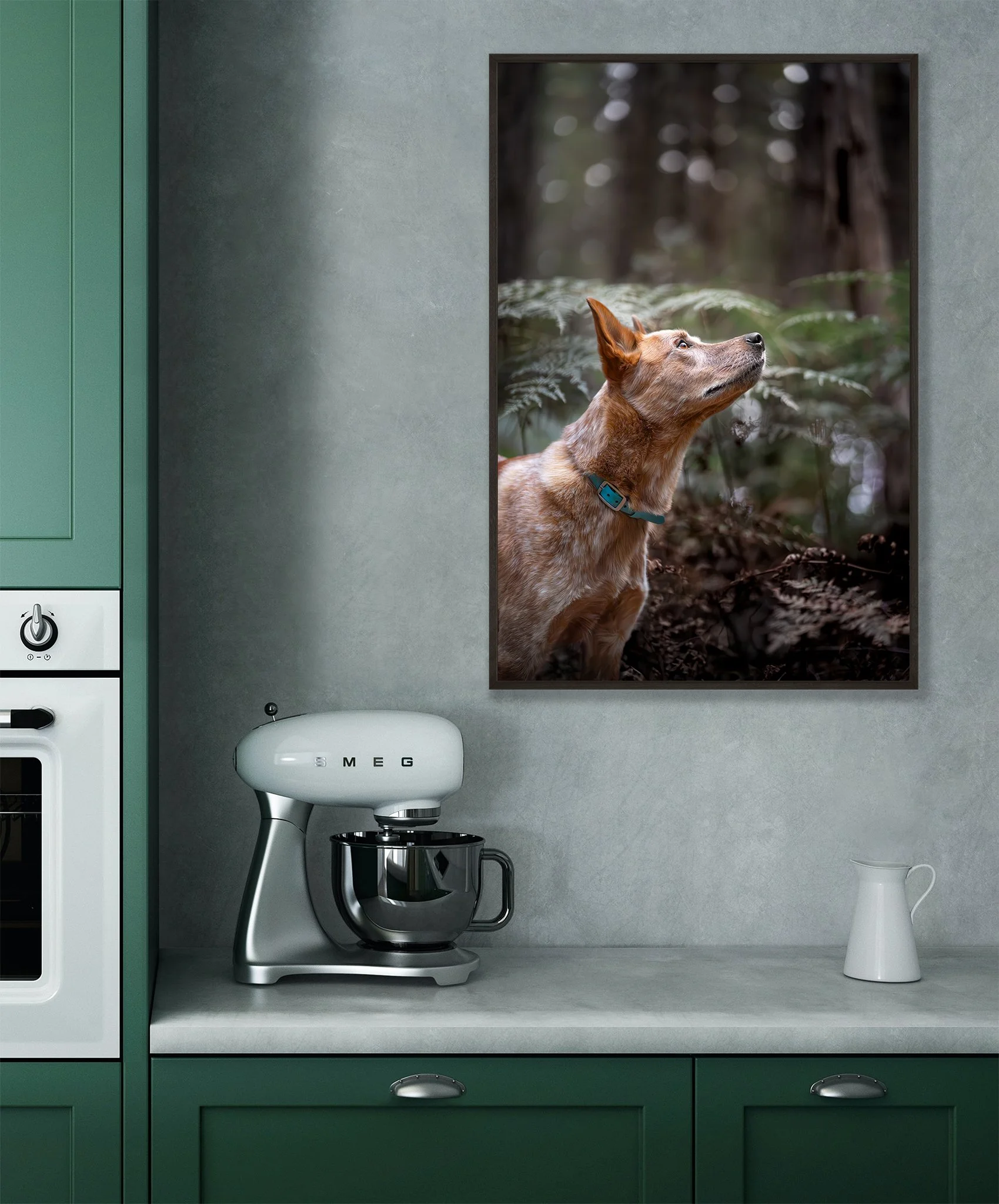 A kitchen with a green cabinet, a white Smeg stand mixer on the countertop, a white pitcher, and a large framed picture of a dog in a forest at the wall.