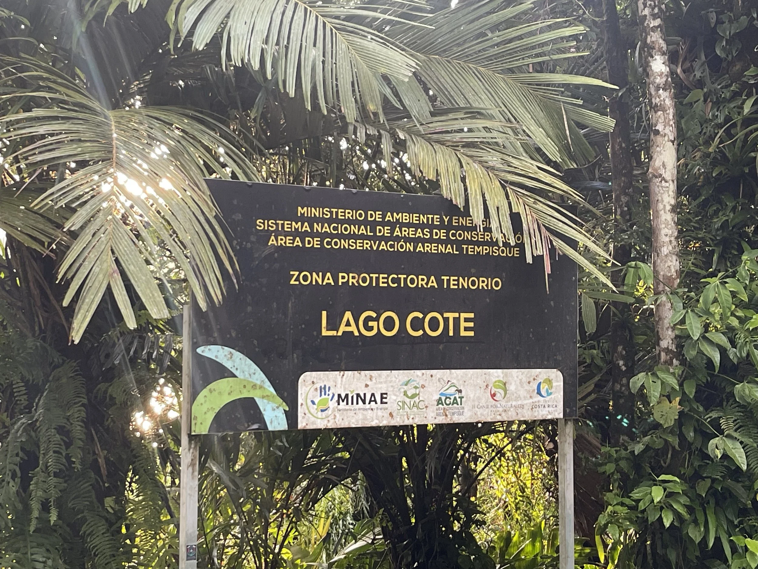 Signboard indicating protection zone at Lake Cote, surrounded by lush tropical plants and trees.