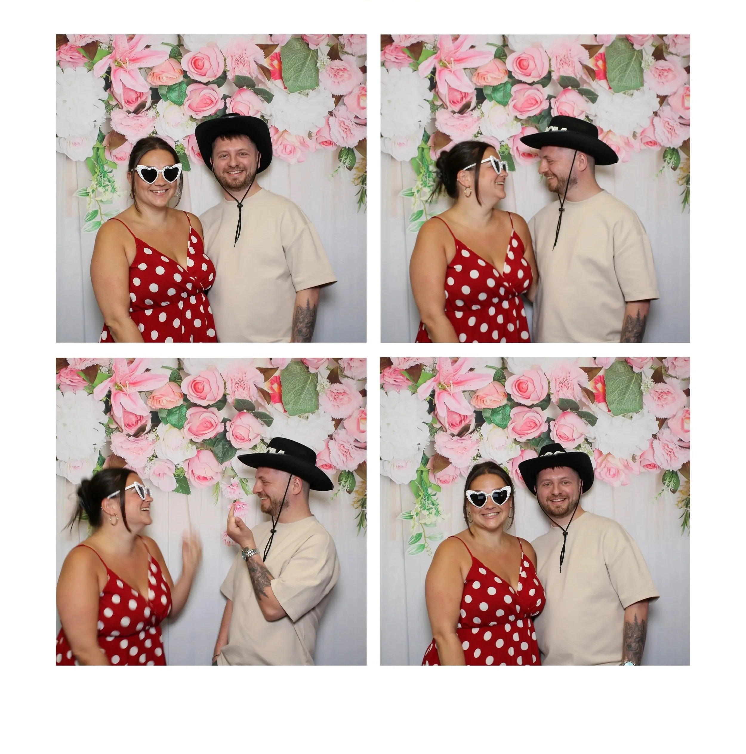 Four people, two men and two women, dressed casually and wearing fun sunglasses, stand against a backdrop of pink and white flowers, smiling and engaging with each other, at a festive event or celebration.