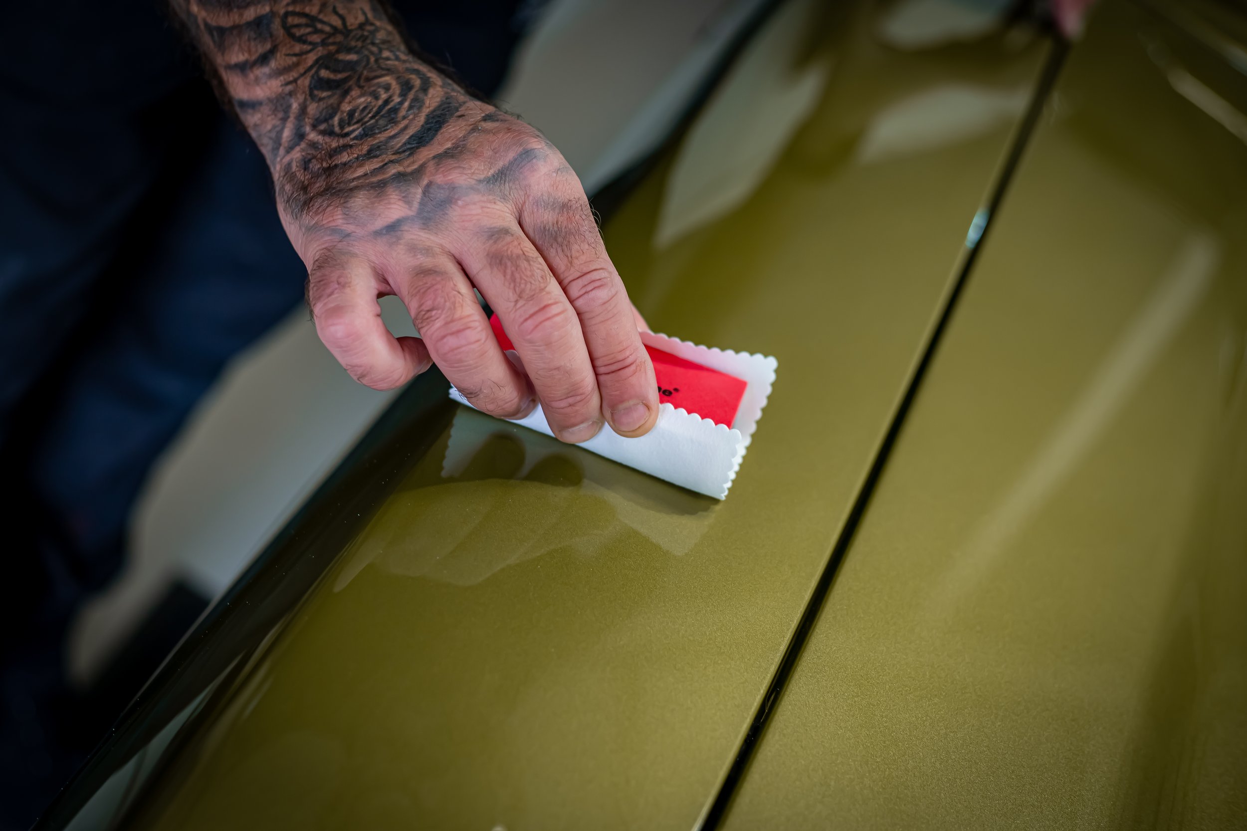 A tattooed hand wiping a surface with a red and white cloth.