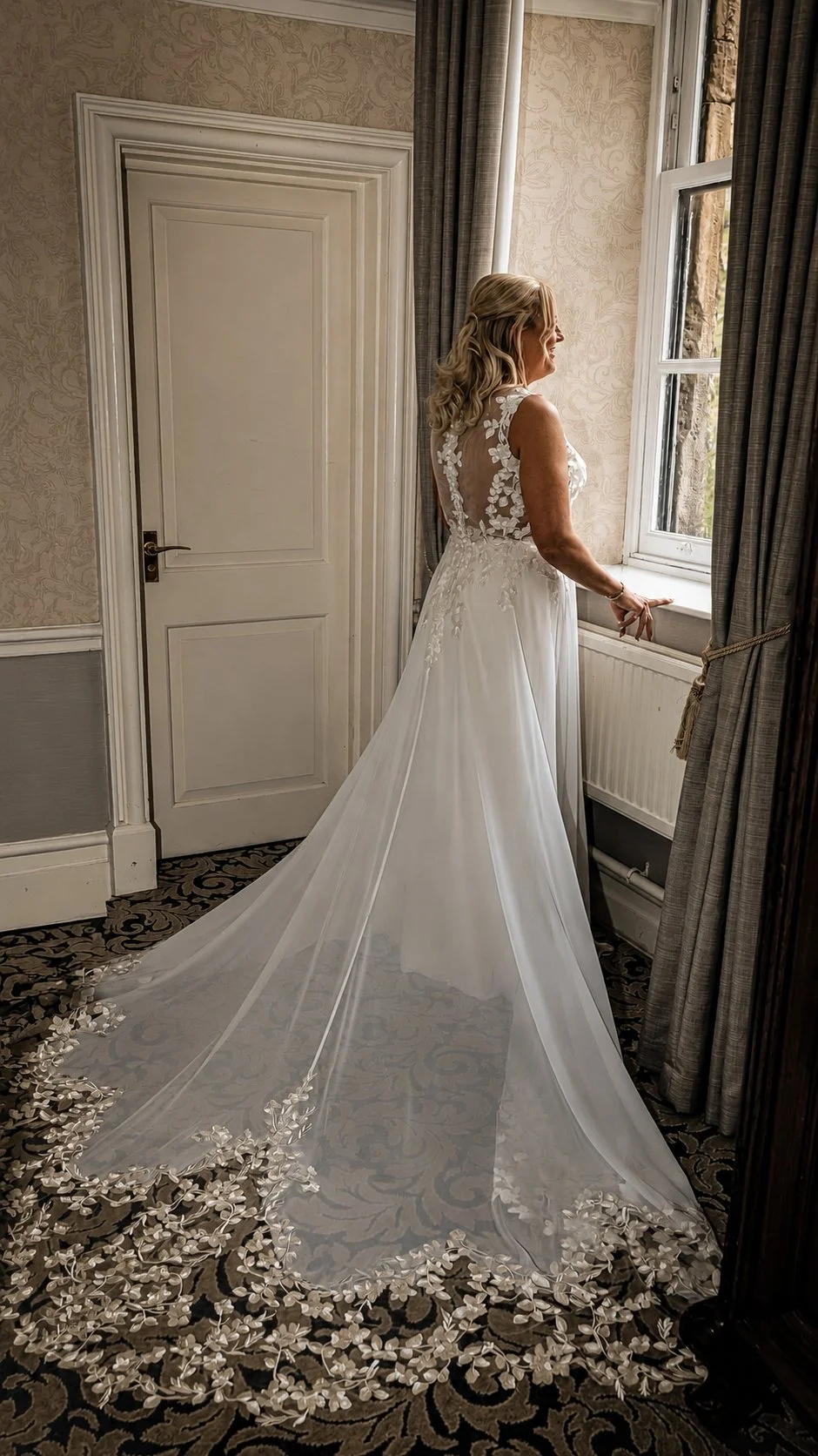 A woman in a wedding dress looking out the window in a decorated room.