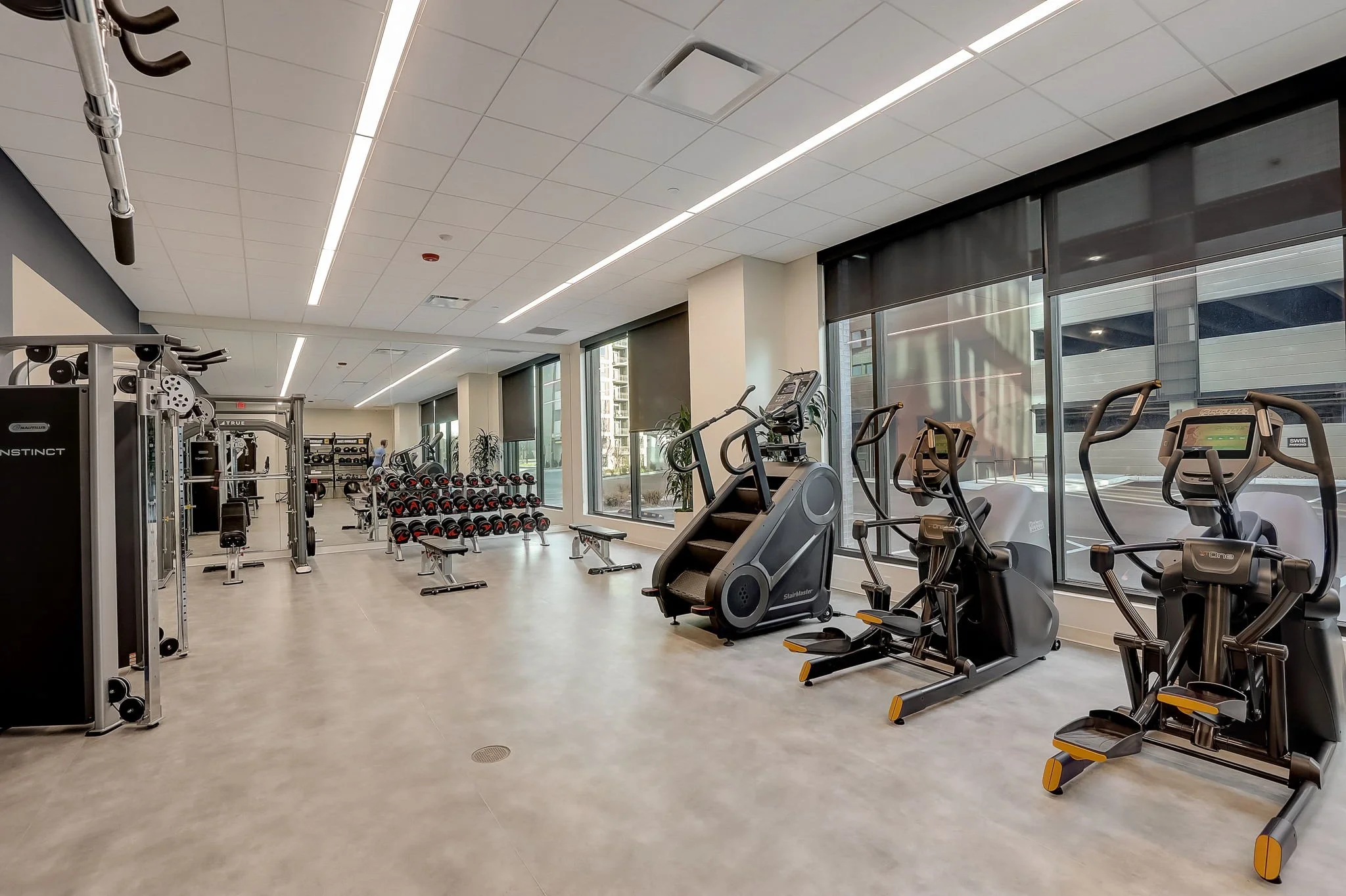 Modern gym with treadmills, elliptical machines, and weight racks.