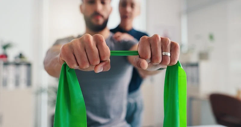 Person performing hand and wrist strengthening exercises using a resistance band under supervision